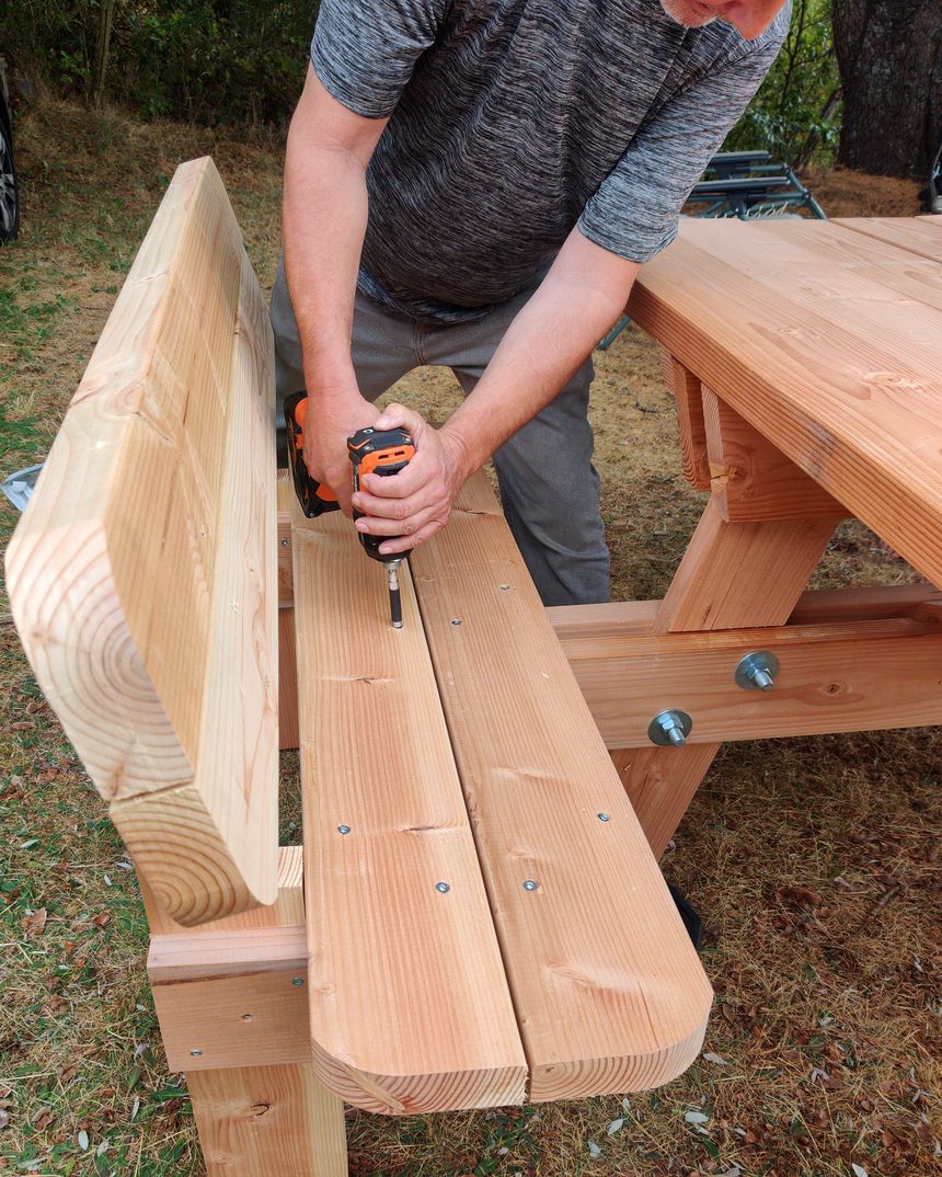 Frédéric Vaudin assemblant une table de pique-nique en Douglas massif à son atelier en Auvergne, visserie boulonnée apparente